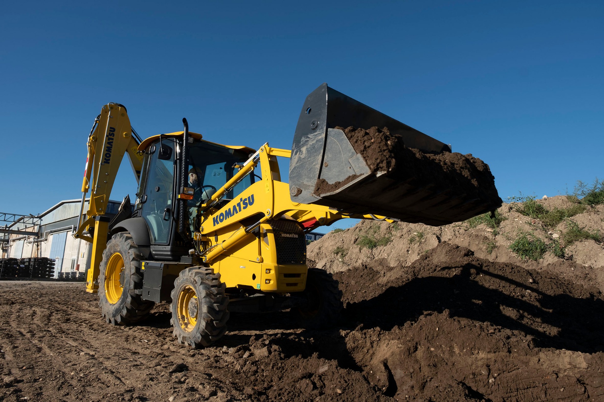 Traktorbagr Komatsu s naloženou lžící při výkopových pracích